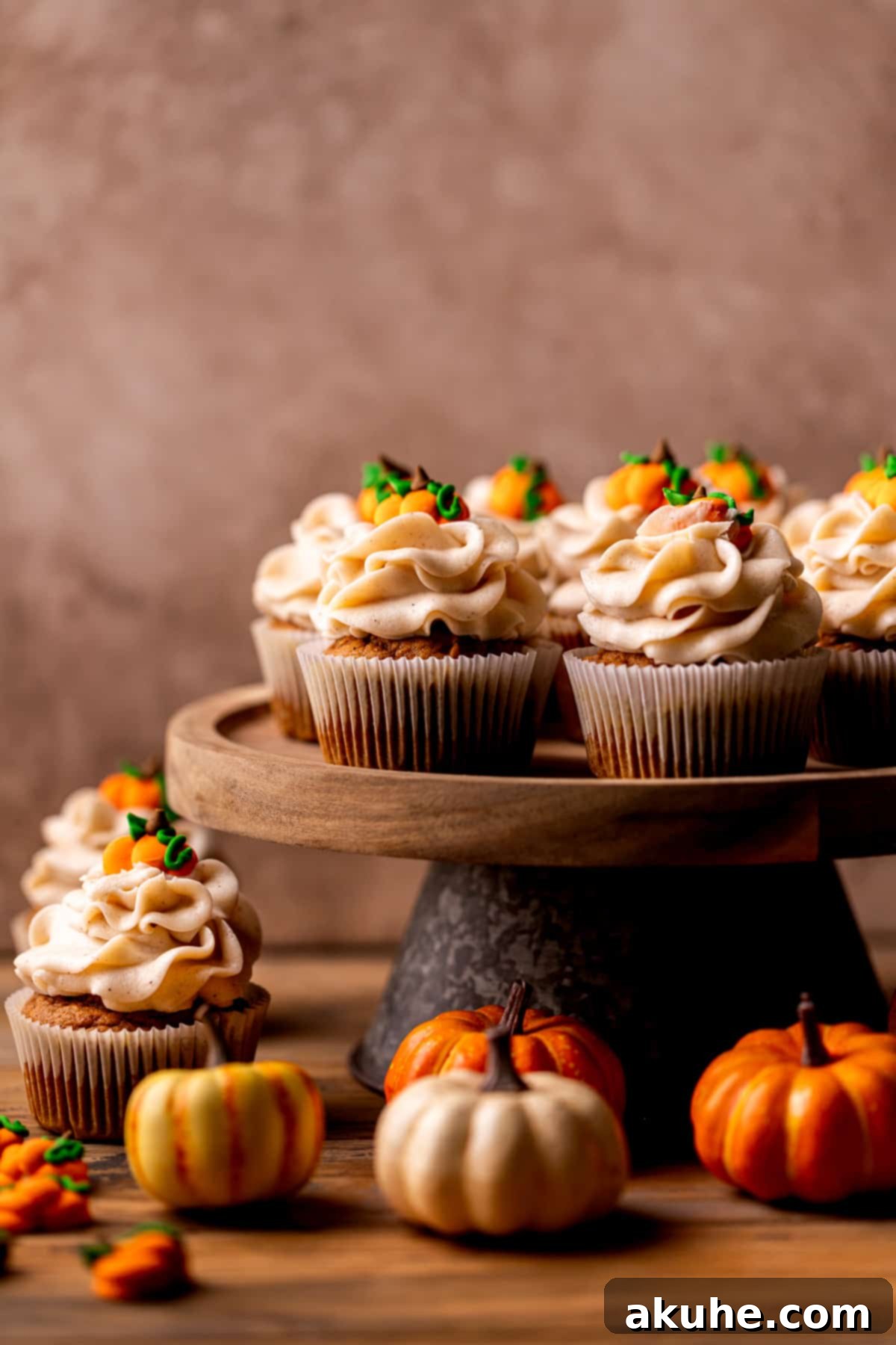 Autumn Pumpkin Spice Cupcakes 3 Beautifully arranged pumpkin cupcakes on a rustic cake stand, ready to be enjoyed as a fall dessert.