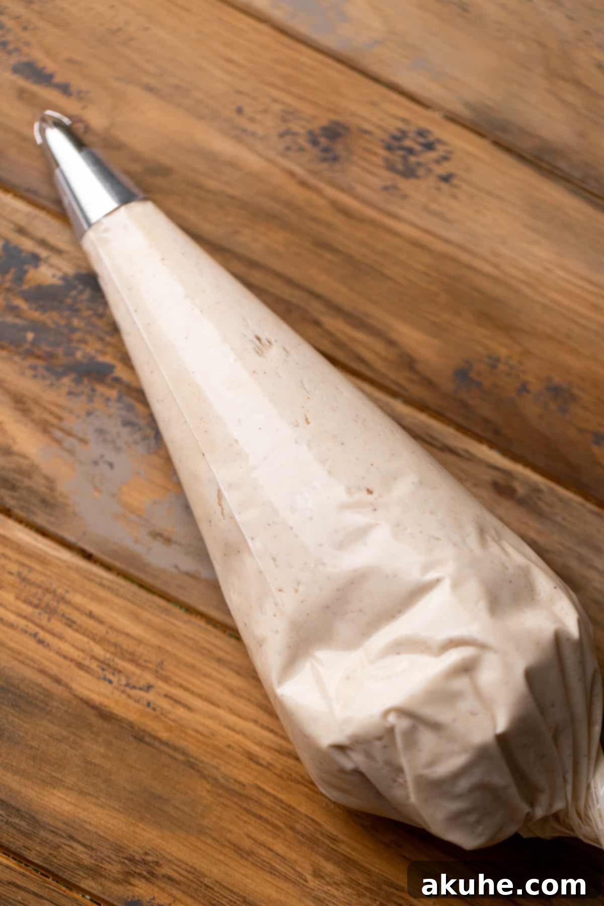 Autumn Pumpkin Spice Cupcakes 8 Creamy cinnamon cream cheese frosting being piped into a pastry bag, ready to adorn the pumpkin cupcakes.