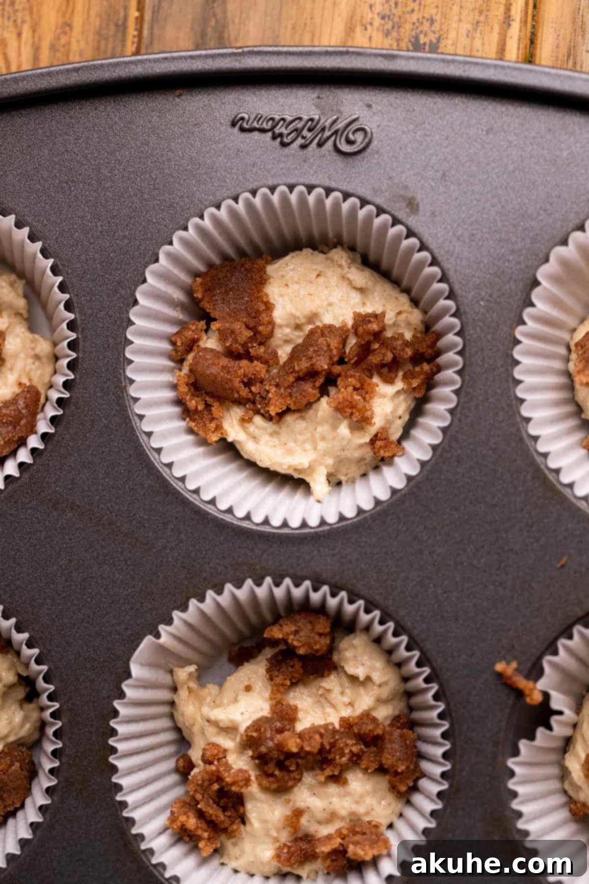 Cupcake pan with liners, half-filled with cinnamon cupcake batter, demonstrating the initial layer before adding the swirl.