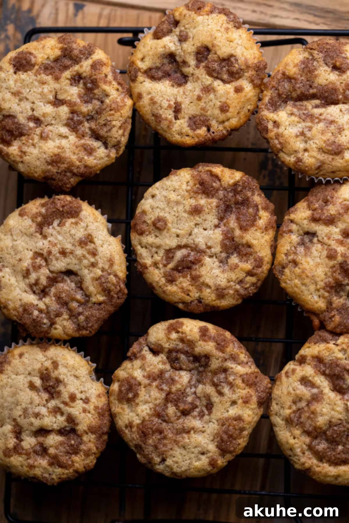 Freshly baked cinnamon roll cupcakes resting on a wire rack, cooling down after coming out of the oven.