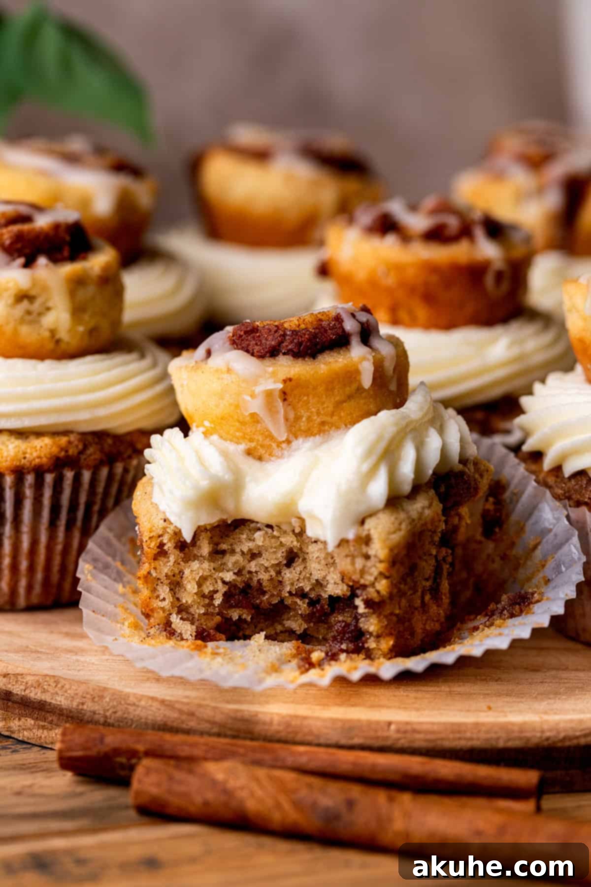 Close-up of a Cinnamon Roll Cupcake with a bite taken out, revealing the soft cake and cinnamon swirl inside.