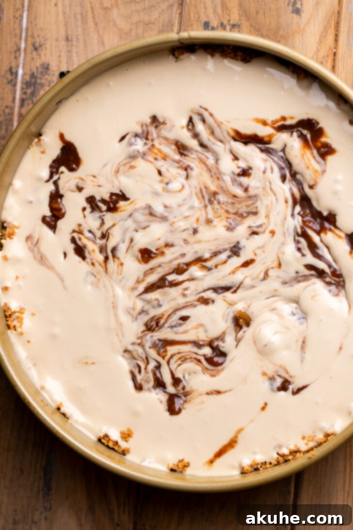 Pecan Pie Cheesecake 6 Pecan pie filling being swirled into cheesecake batter in a springform pan.