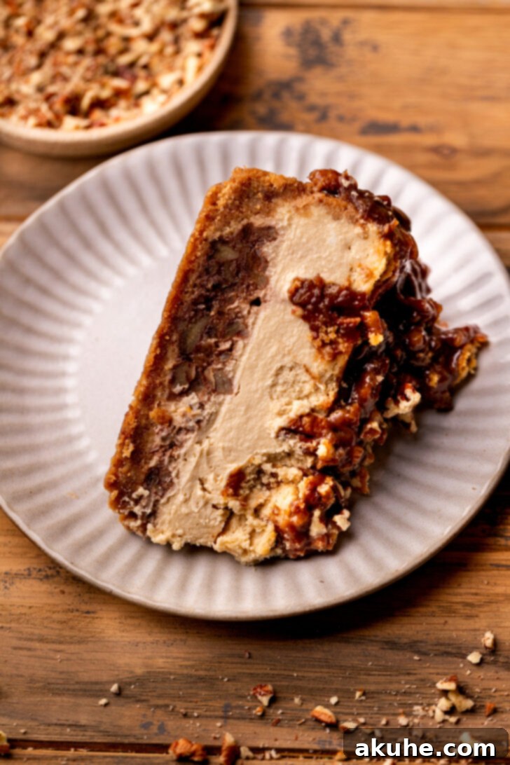 Pecan Pie Cheesecake 8 A slice of pecan pie cheesecake lying on its side on a white plate, showing the layers.