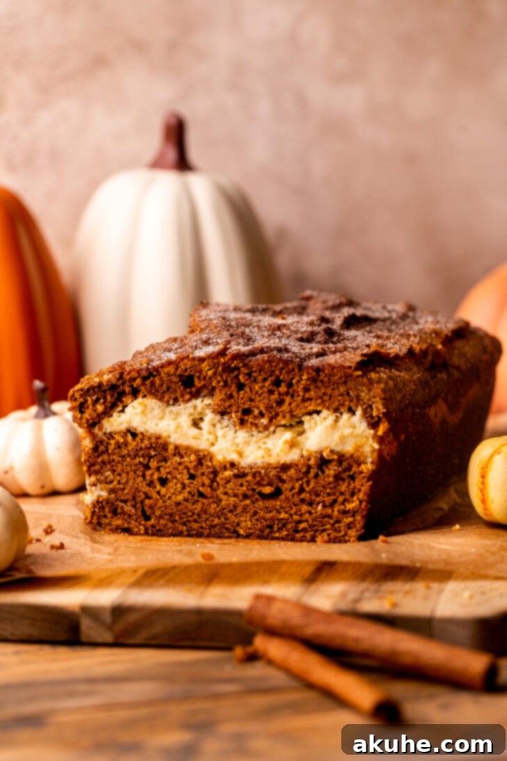 Cream Cheese Swirled Pumpkin Bread 3 Delicious pumpkin cream cheese bread resting on a rustic wood board.