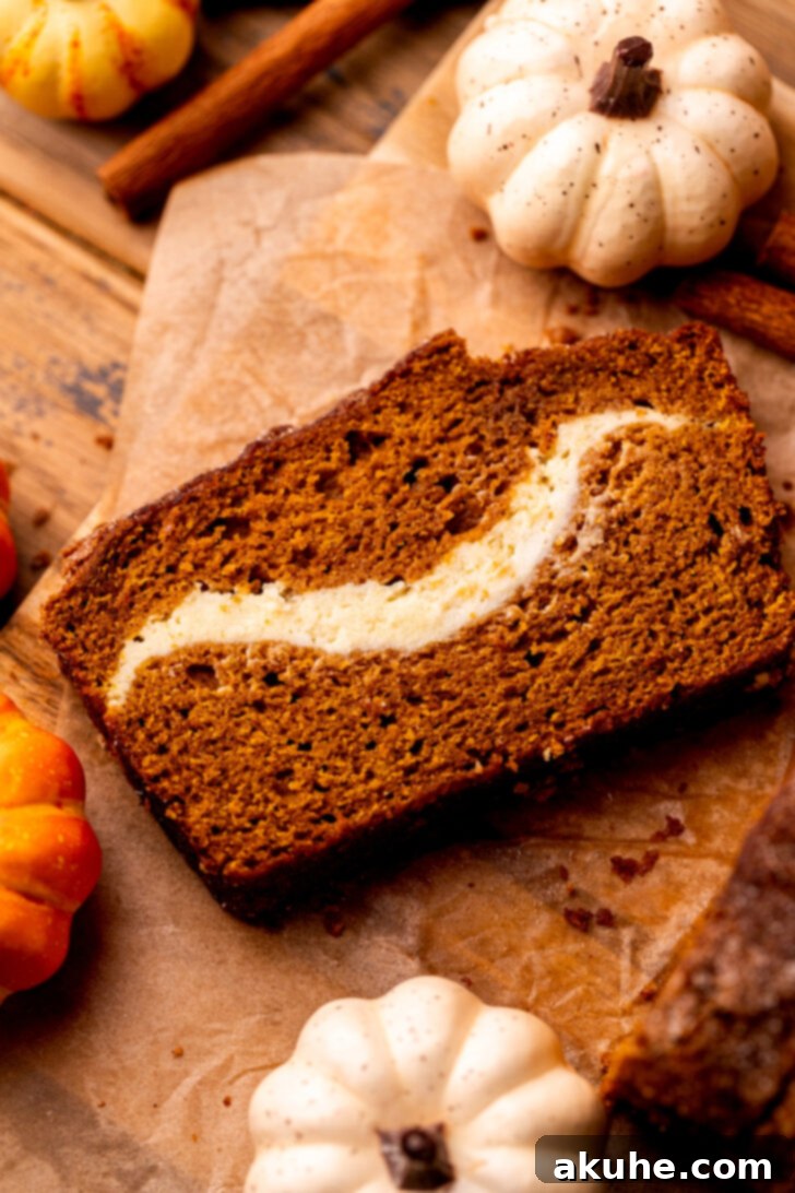 Cream Cheese Swirled Pumpkin Bread 9 Close-up top view of a single slice of pumpkin cream cheese bread on a wood board.