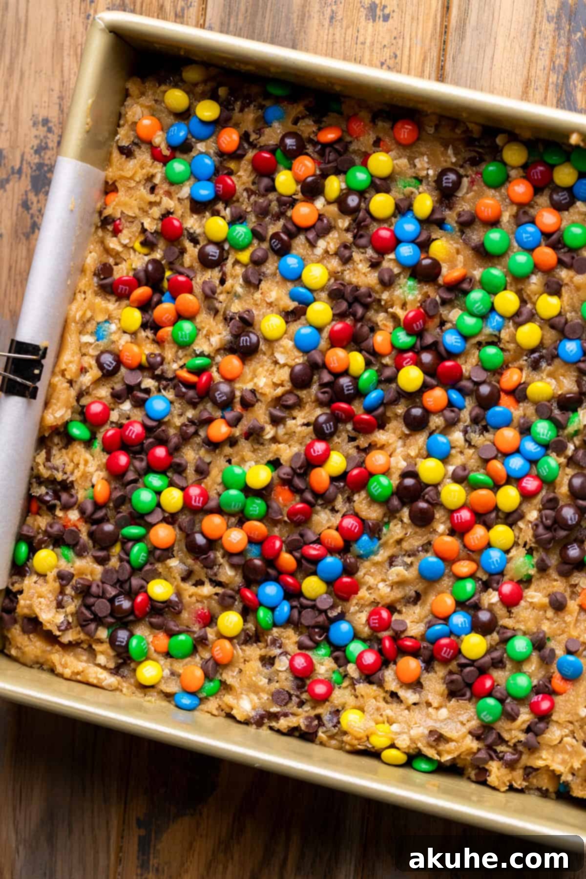 Ultimate Monster Cookie Bars 5 Smoothly spread monster cookie dough nestled in a prepared baking pan, topped with extra M&M's and chocolate chips.