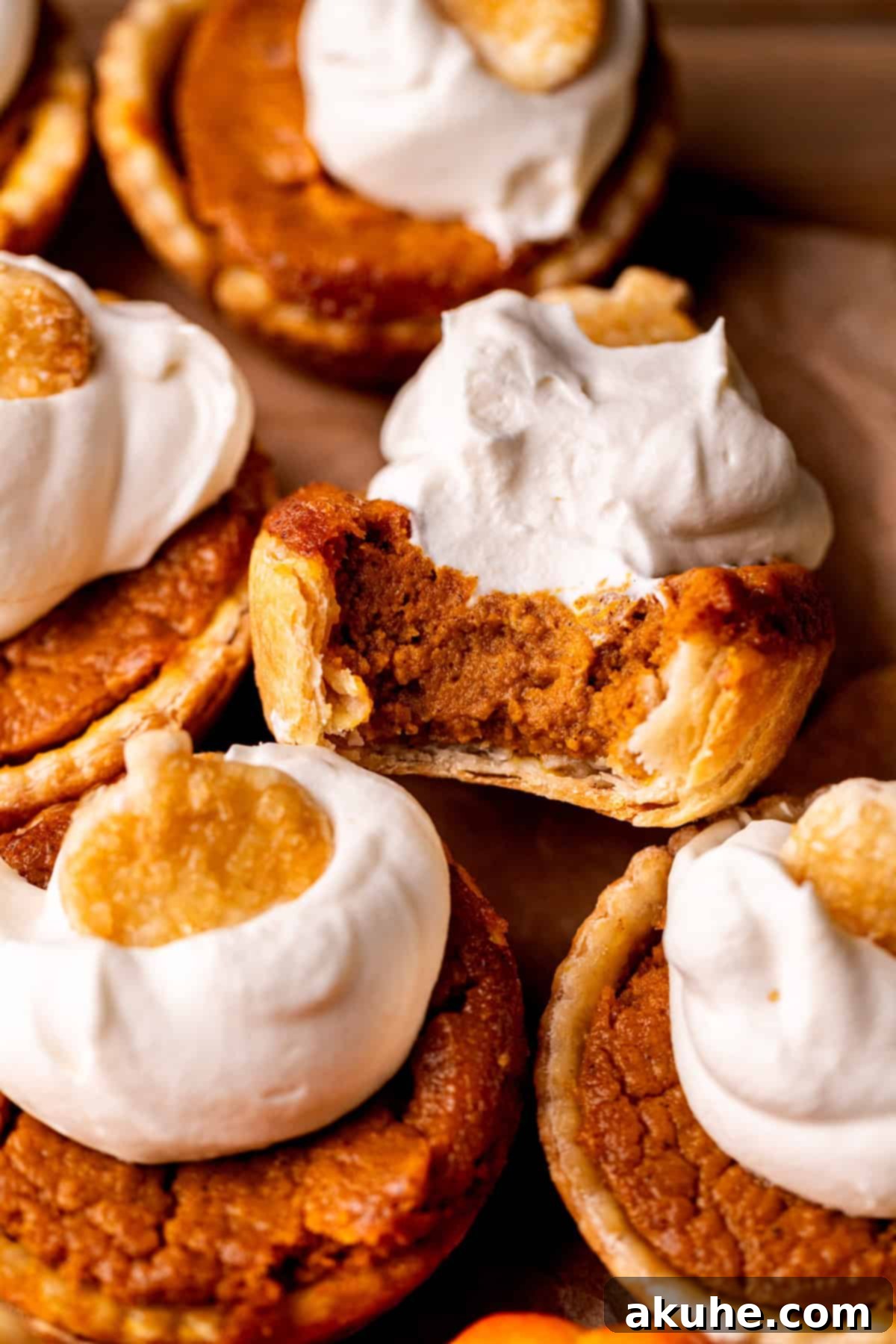 Top view of a bite missing from mini pumpkin pies, showcasing the creamy filling and flaky crust.