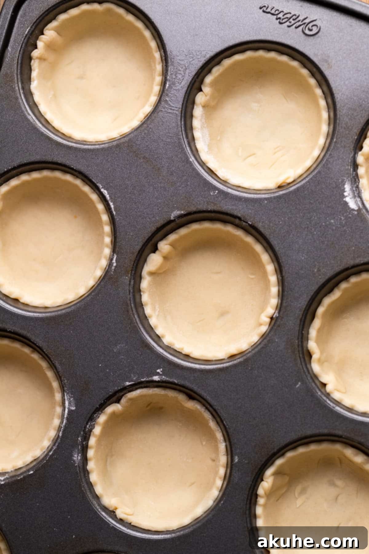 Pie dough circles perfectly fitted into a muffin pan.