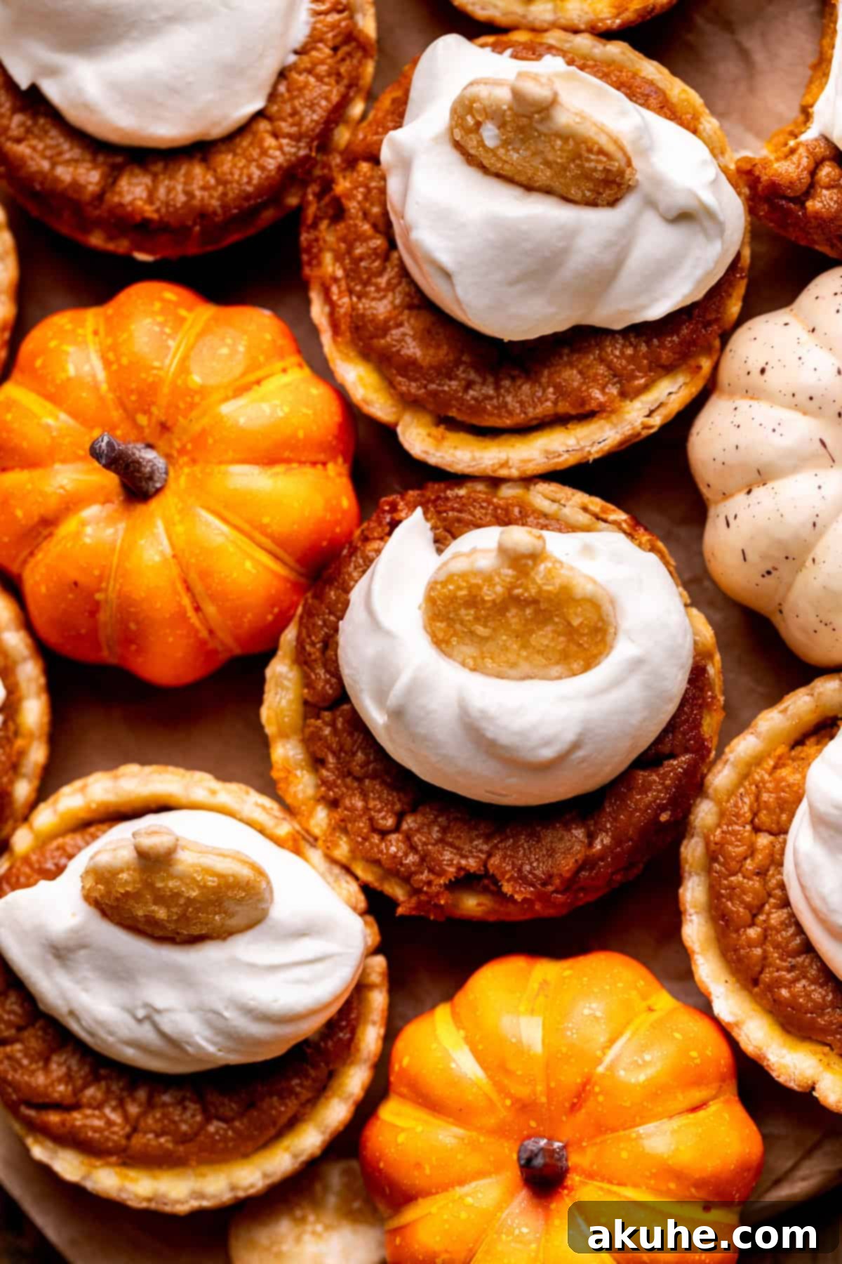 Mini pumpkin pies with whipped cream and decorative pumpkin cutouts on a rustic wood board.