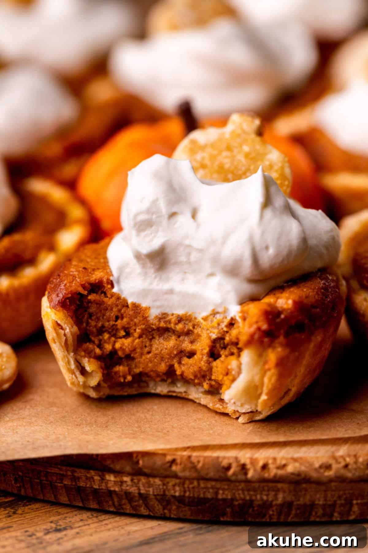 A mini pumpkin pie with a bite taken out, showing the creamy texture and flaky crust.