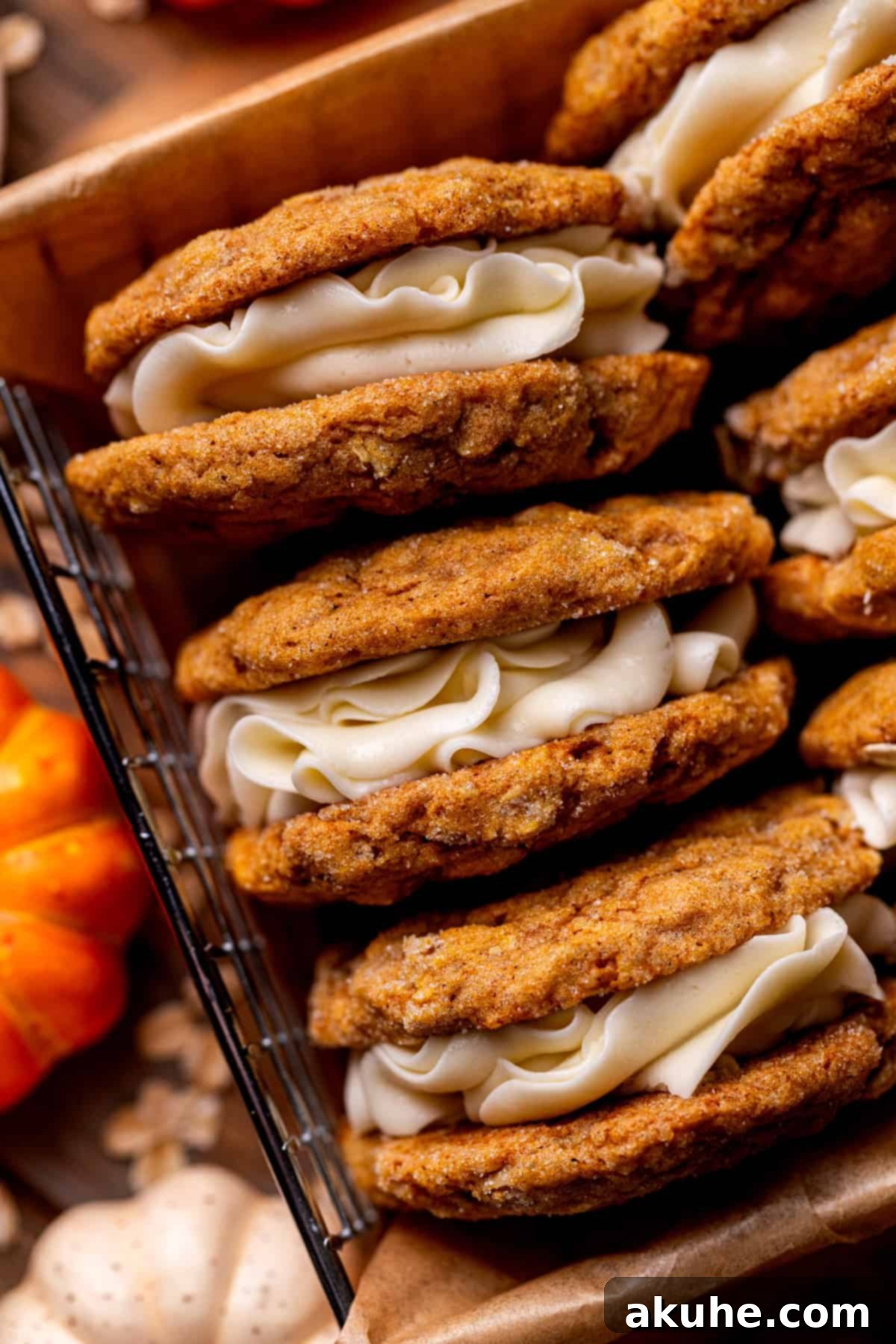Spiced Pumpkin Oatmeal Cream Pies 3 A close-up view of two pumpkin oatmeal cream pies, highlighting the creamy marshmallow filling peeking between the soft cookies.