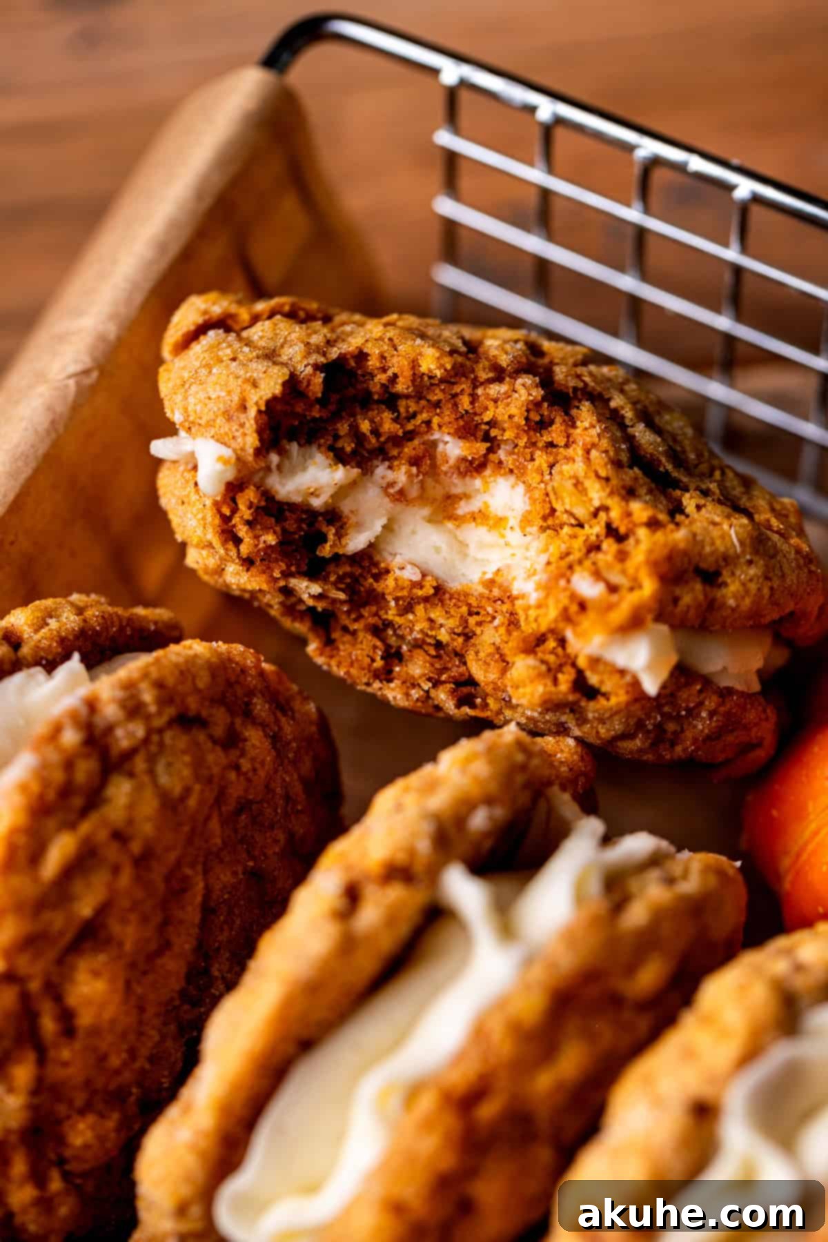 Spiced Pumpkin Oatmeal Cream Pies 9 A close-up of a pumpkin oatmeal cream pie with a bite taken out, revealing the soft cookie and creamy white filling.