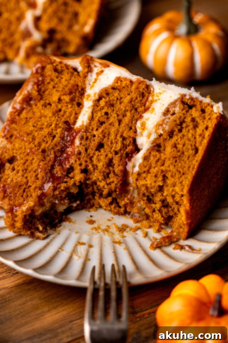 Spiced Pumpkin Caramel Cake 9 A close-up of a pumpkin caramel cake with a bite missing, highlighting its soft texture and the layers of frosting and caramel.