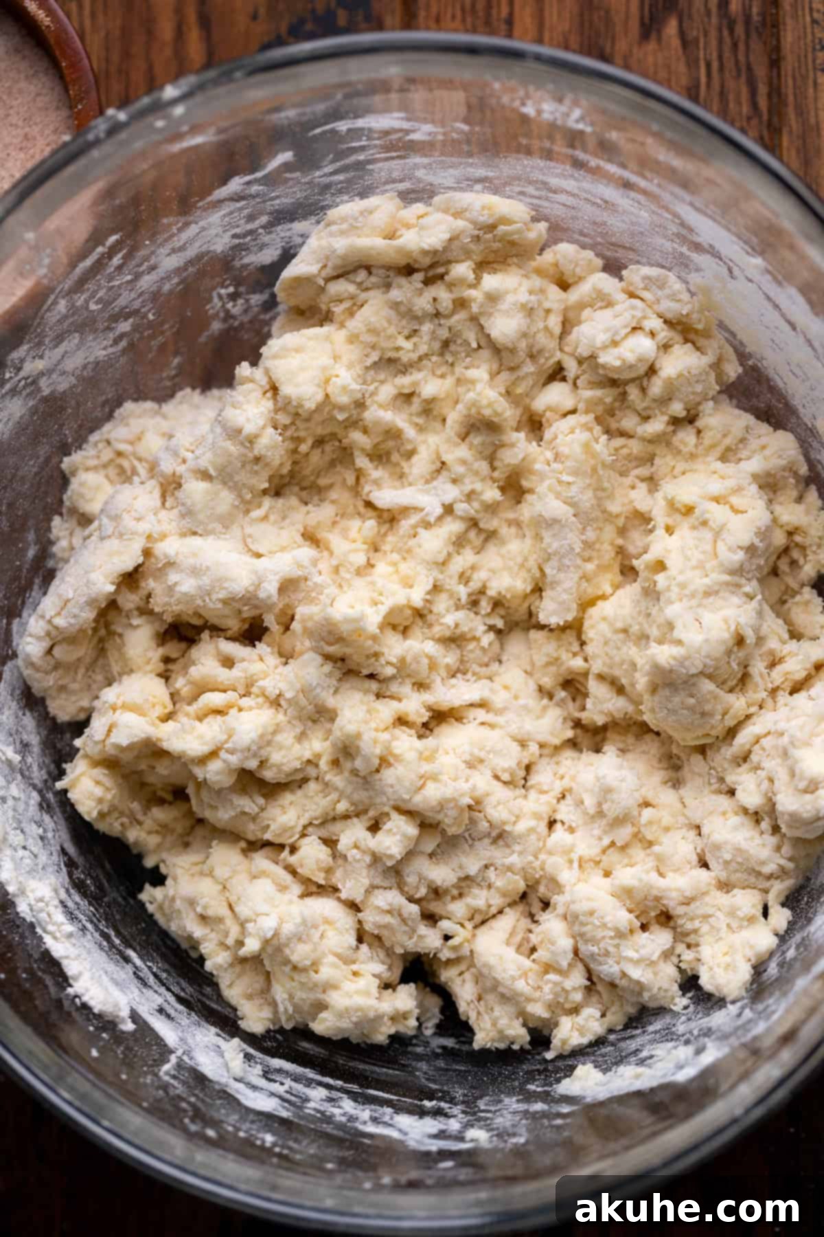 Wet ingredients being mixed into dry ingredients in a glass bowl to form dough.