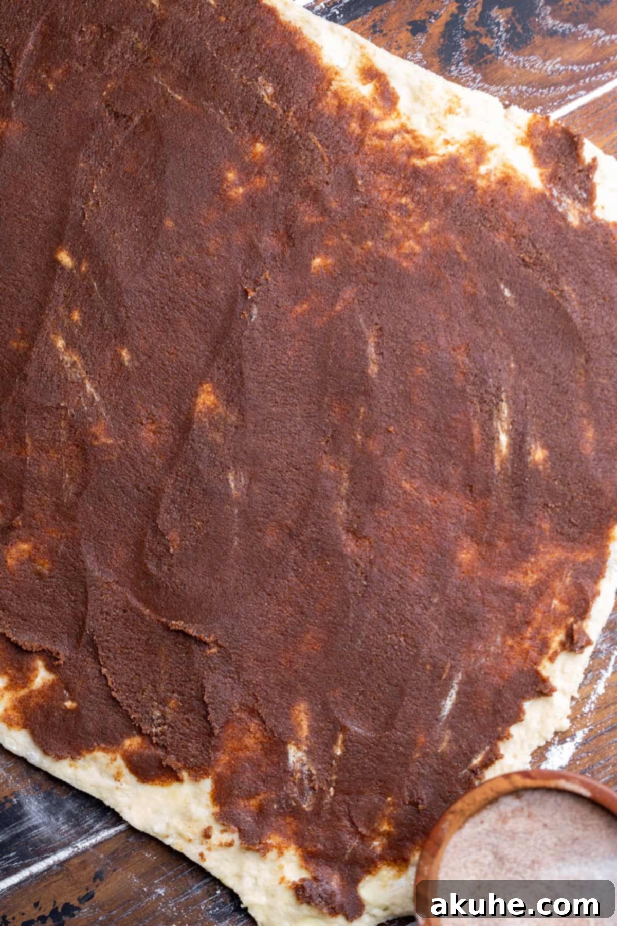 Cinnamon filling generously spread across the rolled-out dough rectangle.