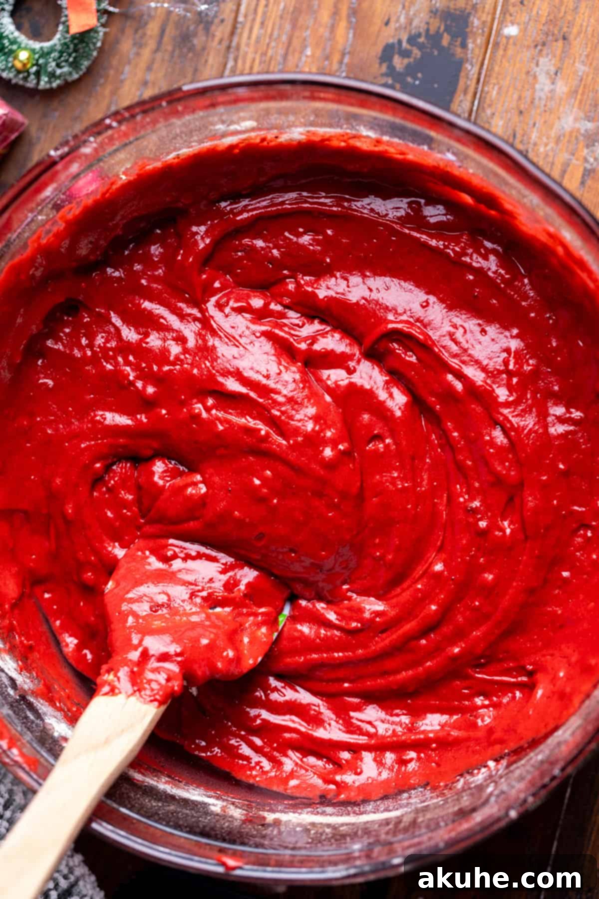 Festive Red Velvet Cake 4 Vibrant red velvet cake batter swirling in a clear glass bowl, showcasing its rich color.