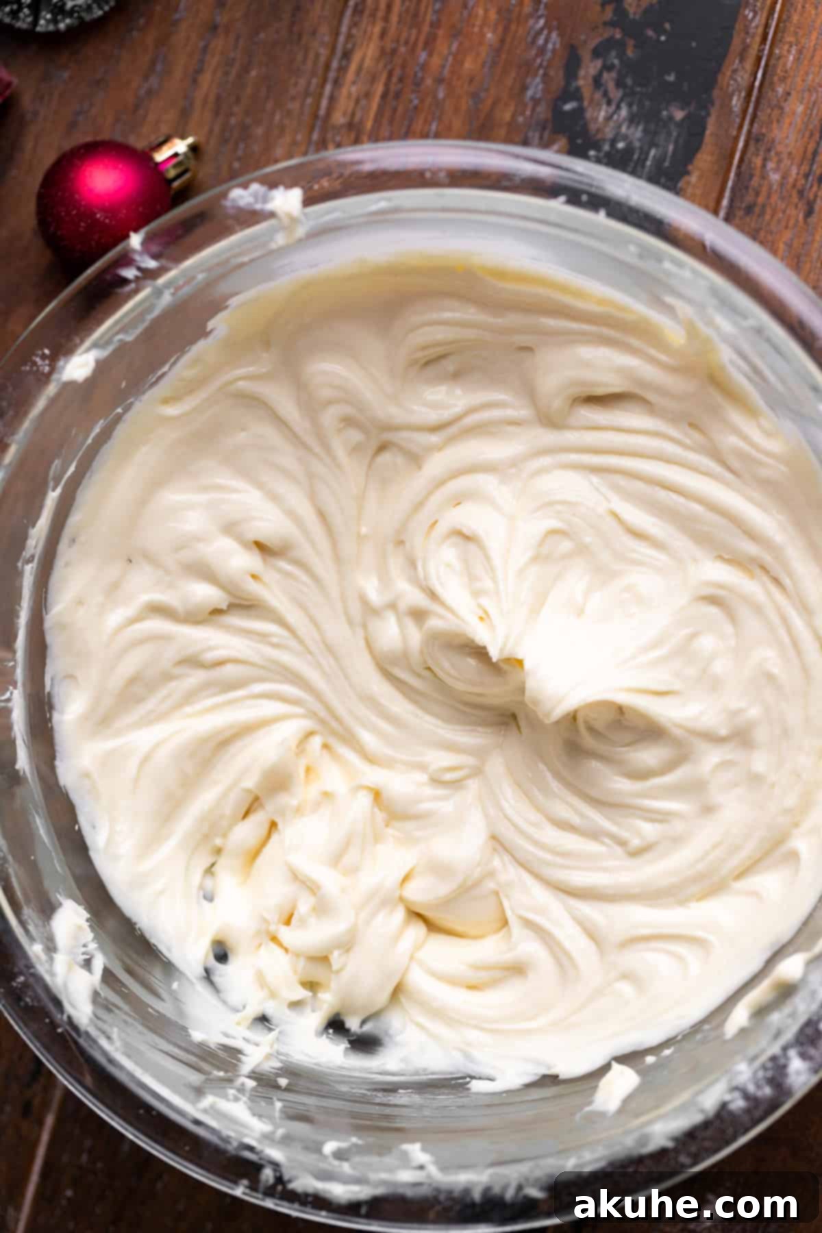 Festive Red Velvet Cake 5 Smooth and creamy cheesecake filling in a clear glass bowl, ready for layering.