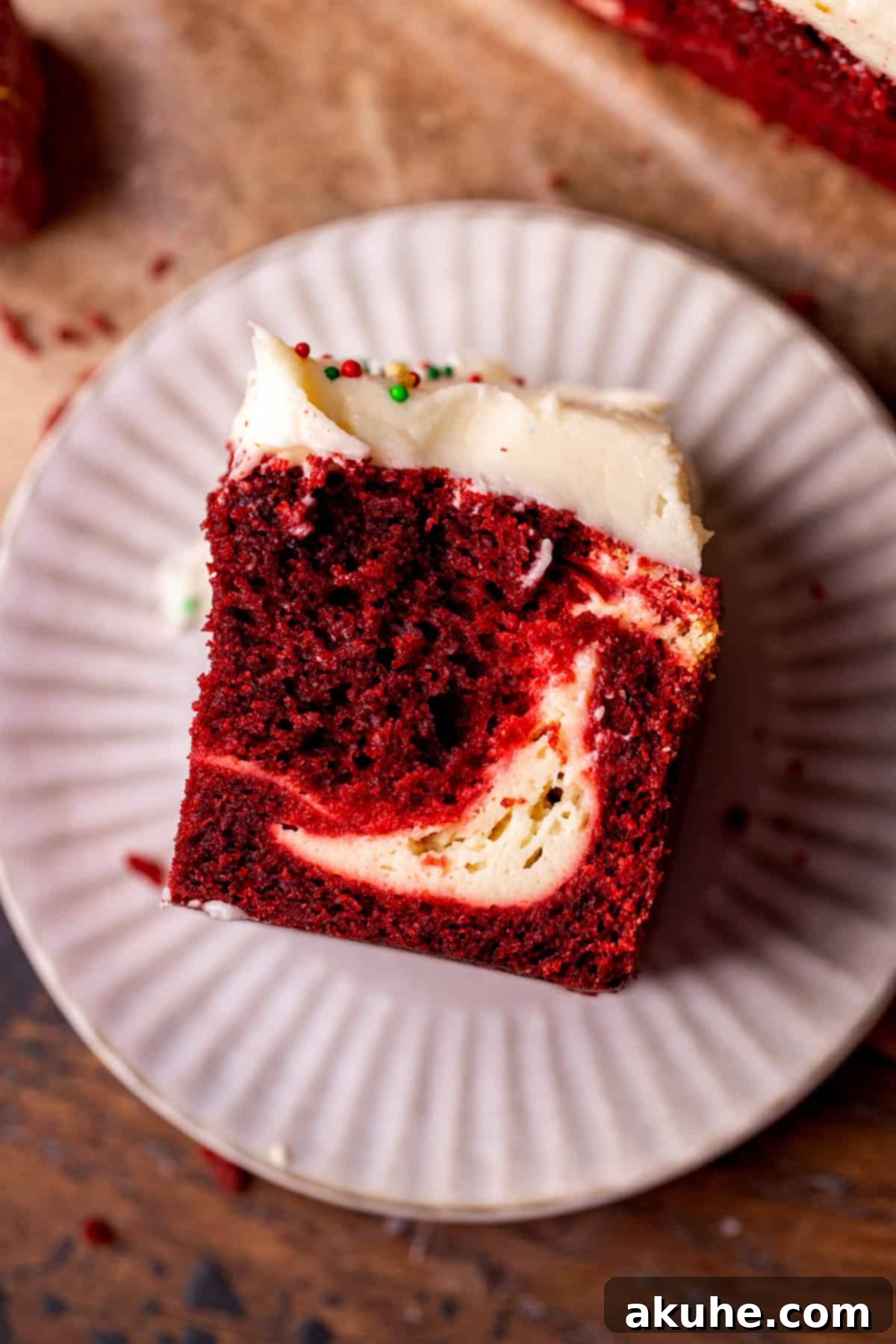 Festive Red Velvet Cake 10 Top view of a delightful slice of Red Velvet Christmas Cake on a plate, garnished with festive sprinkles.
