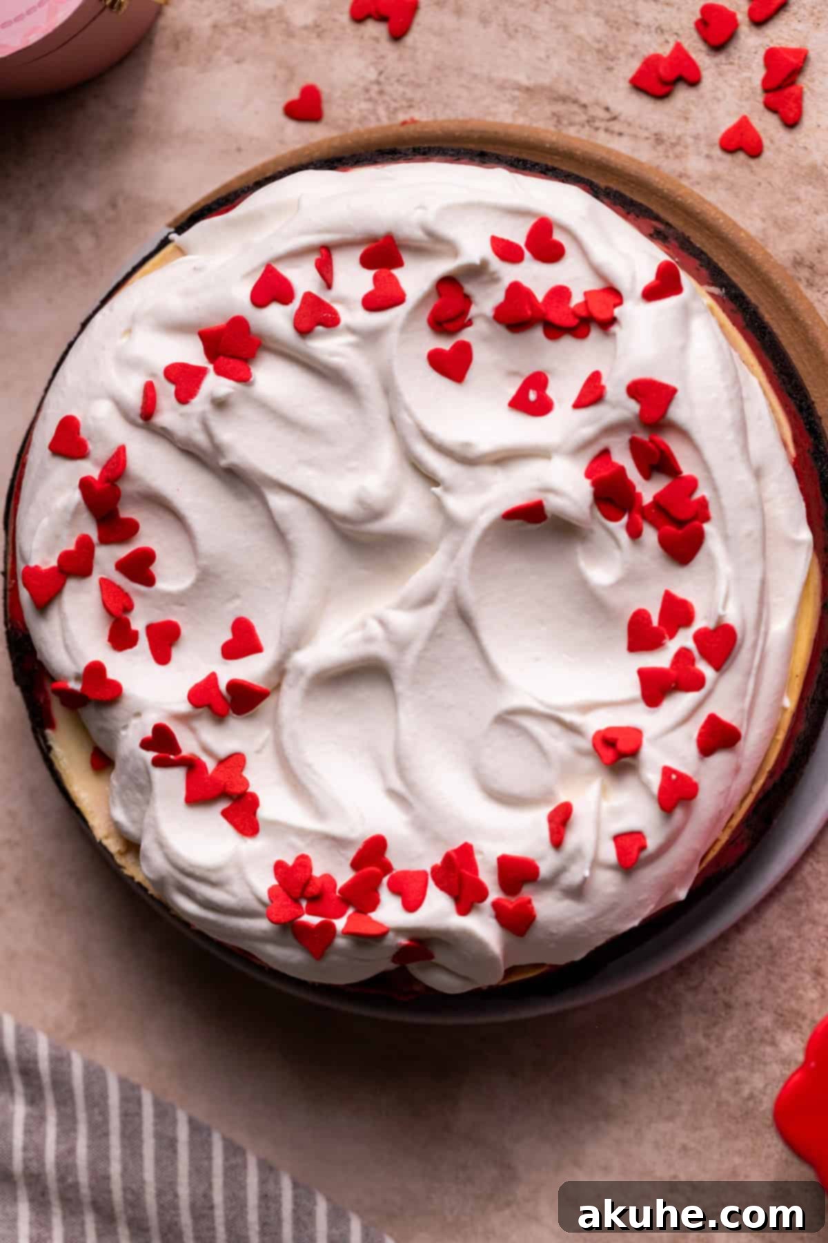 Red Velvet Decadence 11 A beautifully decorated red velvet cheesecake with whipped cream and heart sprinkles.