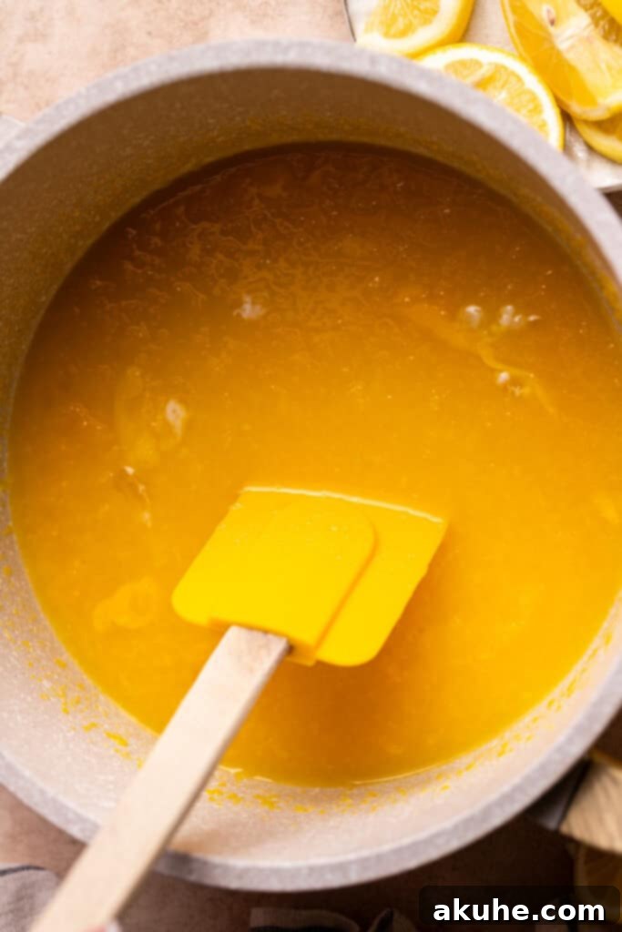 A saucepan on the stovetop containing a vibrant yellow mixture of lemon juice, zest, egg yolks, sugar, and a pinch of salt, ready for heating to create homemade lemon curd.