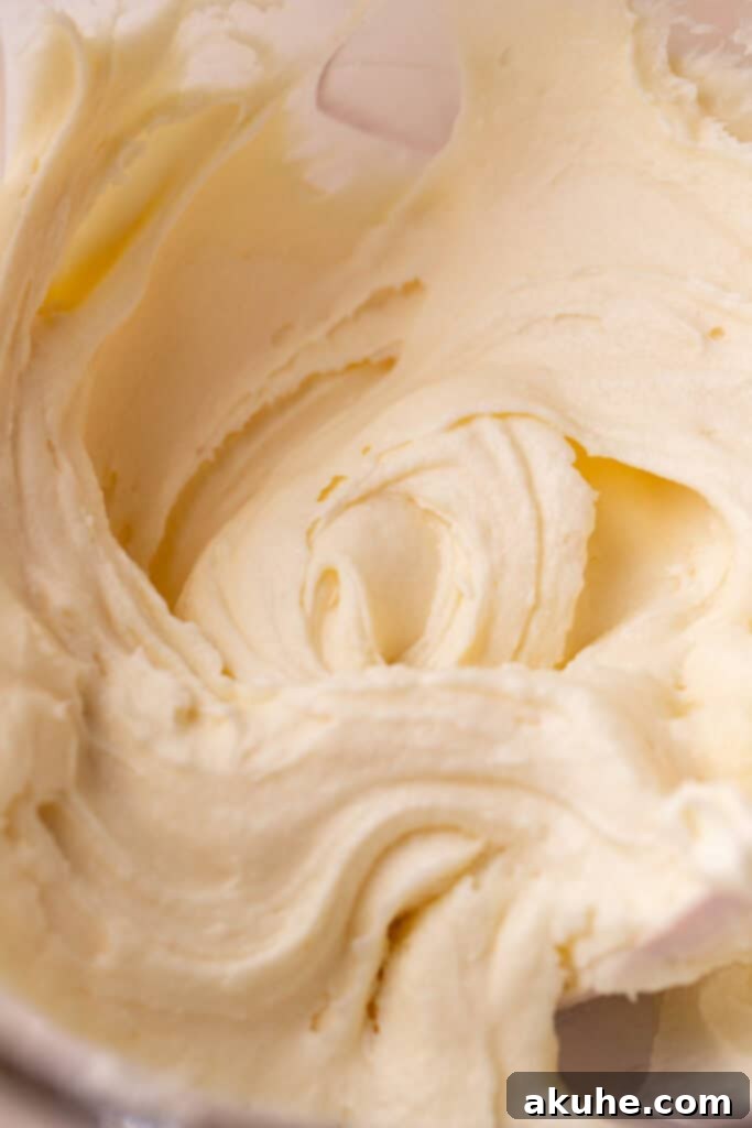 Smooth and fluffy cream cheese frosting in a clear glass mixing bowl.