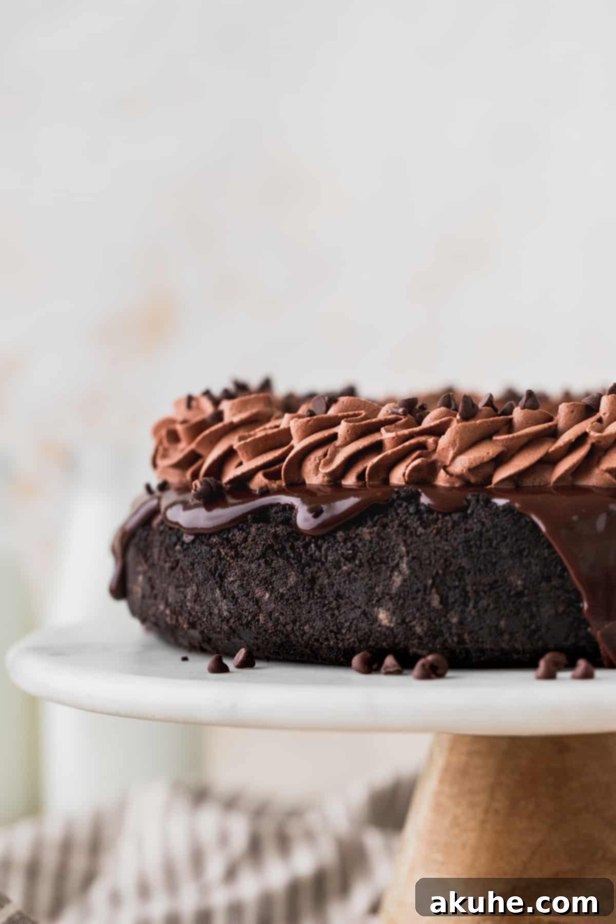 Decadent Triple Chocolate Cheesecake 3 Full triple chocolate cheesecake on an elegant marble cake stand, showcasing its beautiful layers.