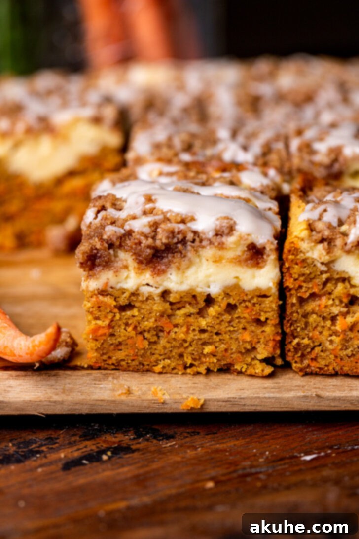 Spiced Carrot Coffee Cake 2 Side view of a freshly baked carrot cake coffee cake, showing distinct layers of cake, cream cheese, and cinnamon crumble, drizzled with vanilla icing.
