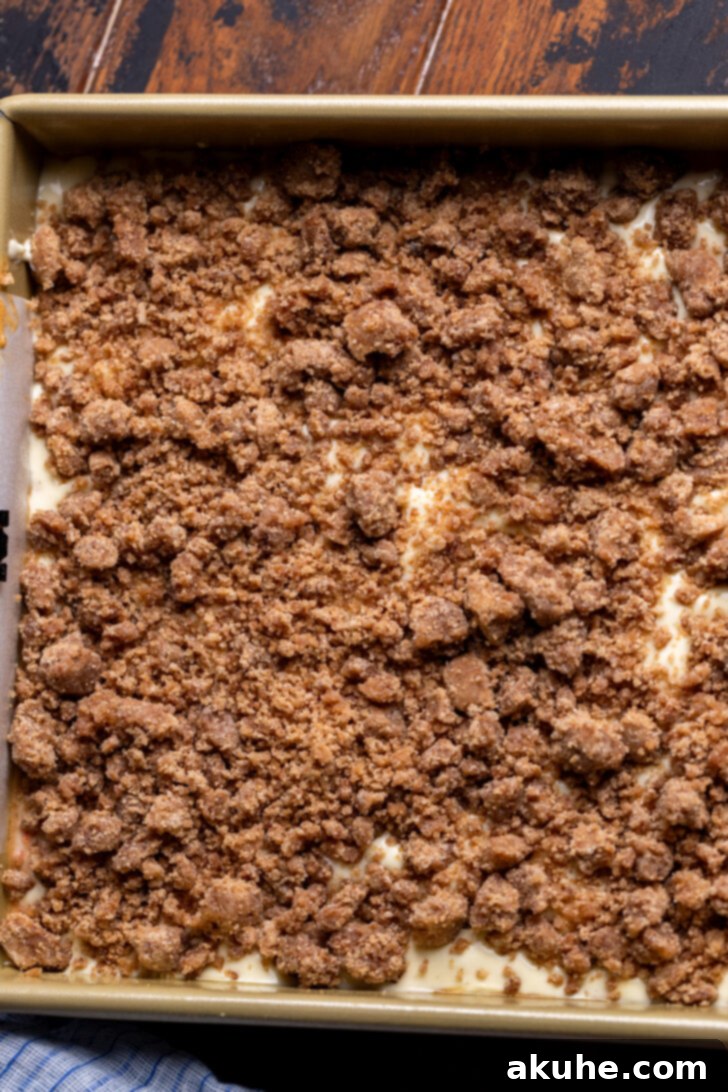 Spiced Carrot Coffee Cake 9 Golden cinnamon crumble generously sprinkled over the cream cheese layer in a baking pan.