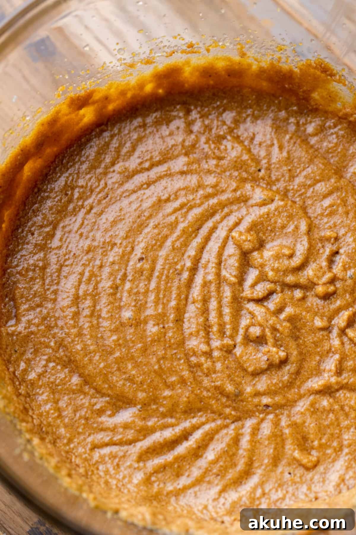 Close-up of the wet ingredients mixture in a clear glass bowl, showing its smooth, emulsified texture before dry ingredients are added.
