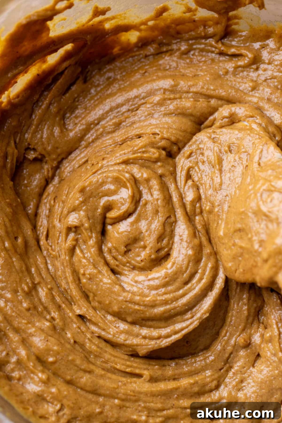 Thick, spiced gingerbread cake batter in a glass mixing bowl, ready for baking.