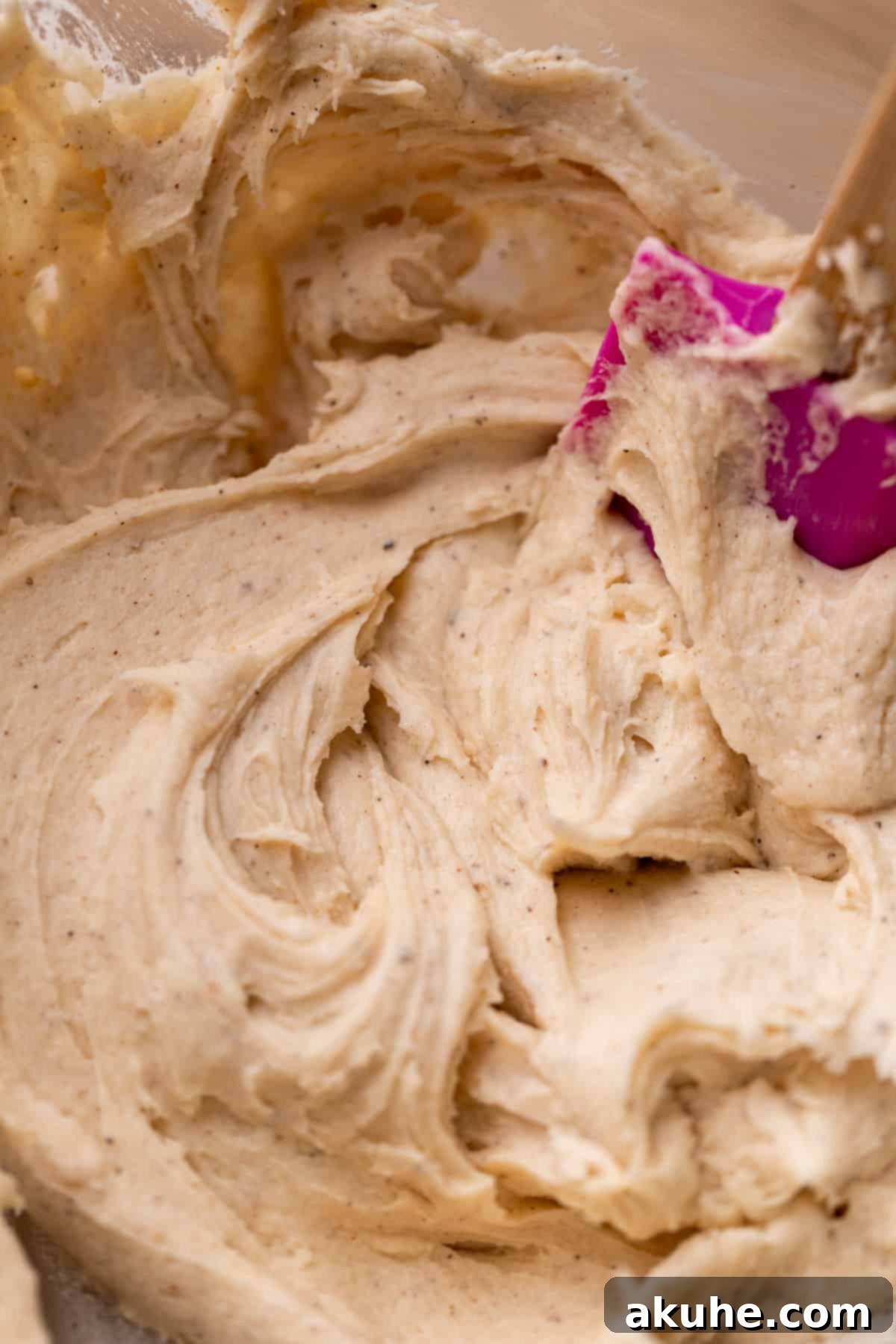 Smooth, light brown browned butter cream cheese icing in a glass bowl, ready to be spread.