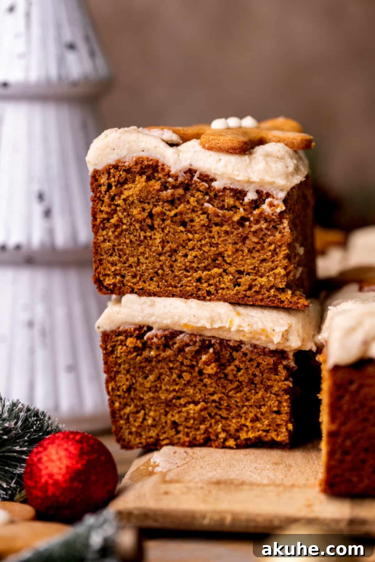 A stack of two perfectly cut slices of gingerbread cake, revealing the moist interior and generous frosting.