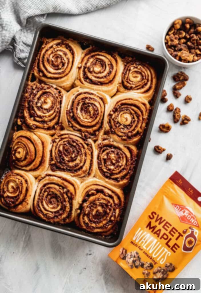 Nutty Cinnamon Swirls 4 Walnut cinnamon rolls rising in a pan, before being topped with icing.