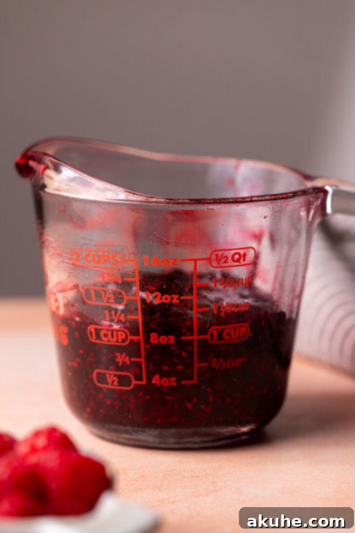 Effortless Raspberry Preserve 7 Freshly made raspberry jam measured in a glass cup, showing the final yield of 1 1/4 cups.