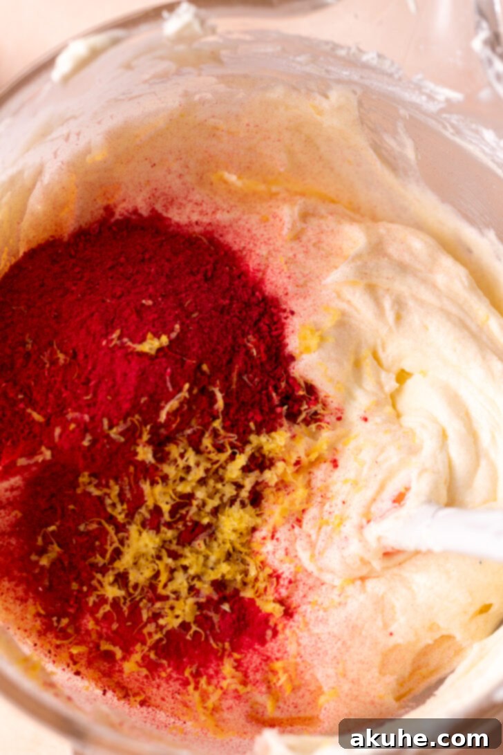 Finely ground freeze-dried raspberries in a small bowl, resembling a vibrant pink powder, ready to be incorporated into the frosting.