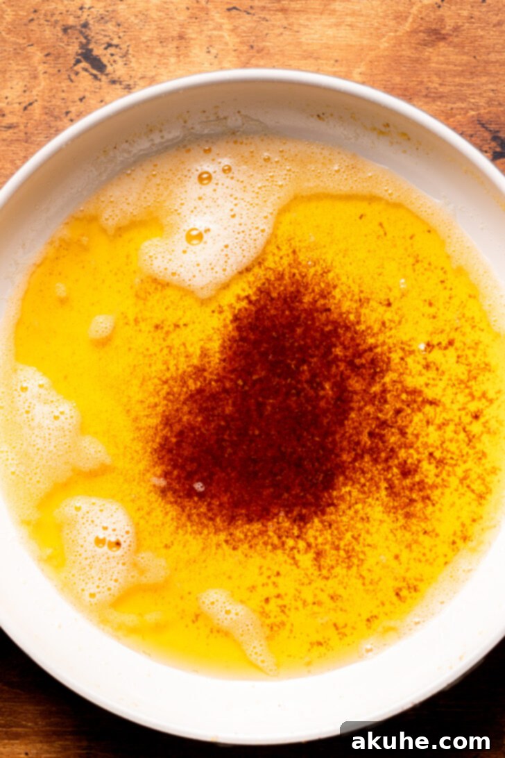 Achieving Golden Brown Butter 3 Top-down view of brown butter simmering gently in a stainless steel pan, with visible amber milk solids at the bottom.