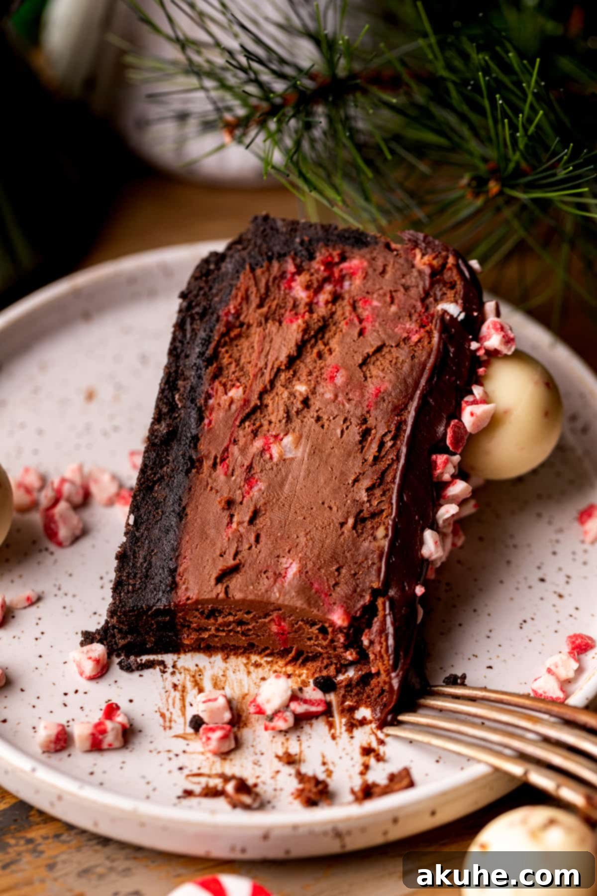 Peppermint Bark Cheesecake 9 A single, perfectly cut slice of chocolate peppermint cheesecake presented elegantly on a white plate, showcasing its pristine texture.