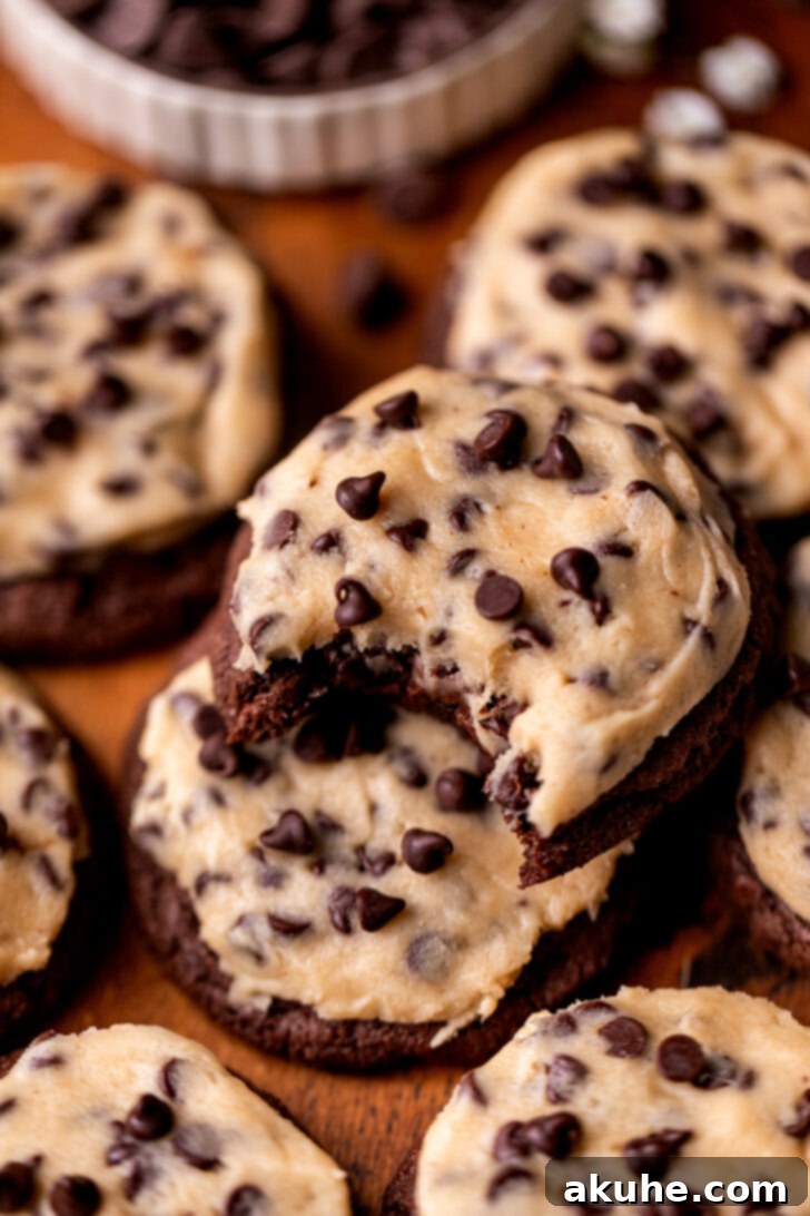 Cookie Dough Stuffed Cookies 2 Bite missing from a stack of delicious cookie dough cookies, showcasing the layers of chocolate cookie and edible cookie dough.