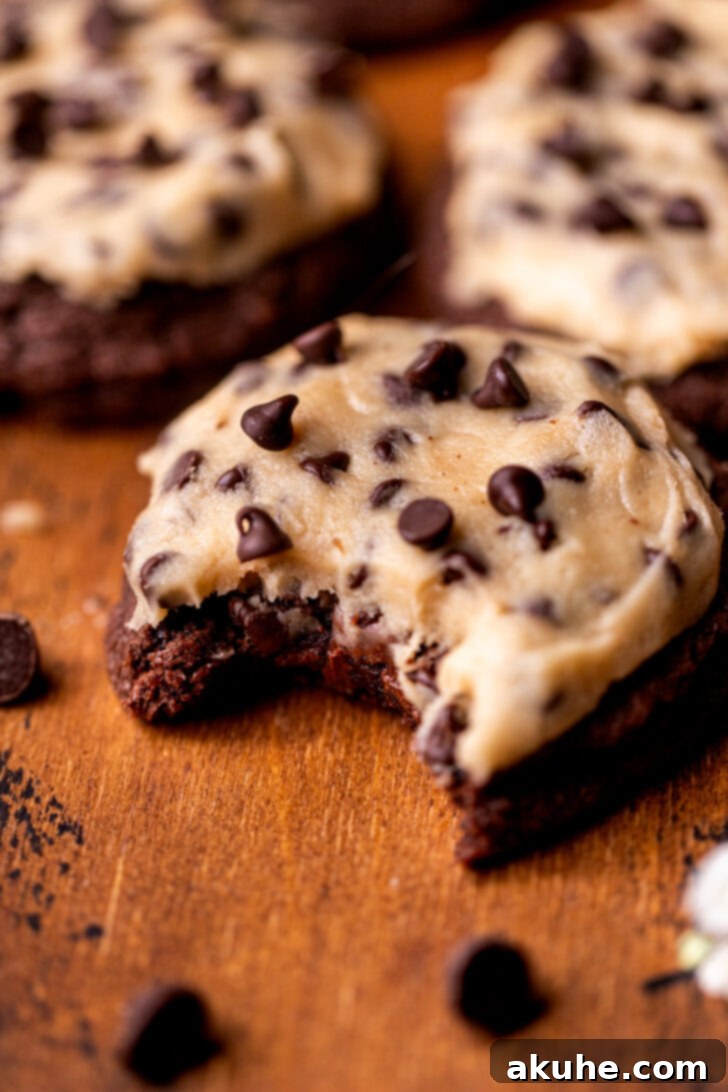 Cookie Dough Stuffed Cookies 11 A delicious cookie with one bite missing, showcasing the tempting layers of chocolate cookie and edible cookie dough.