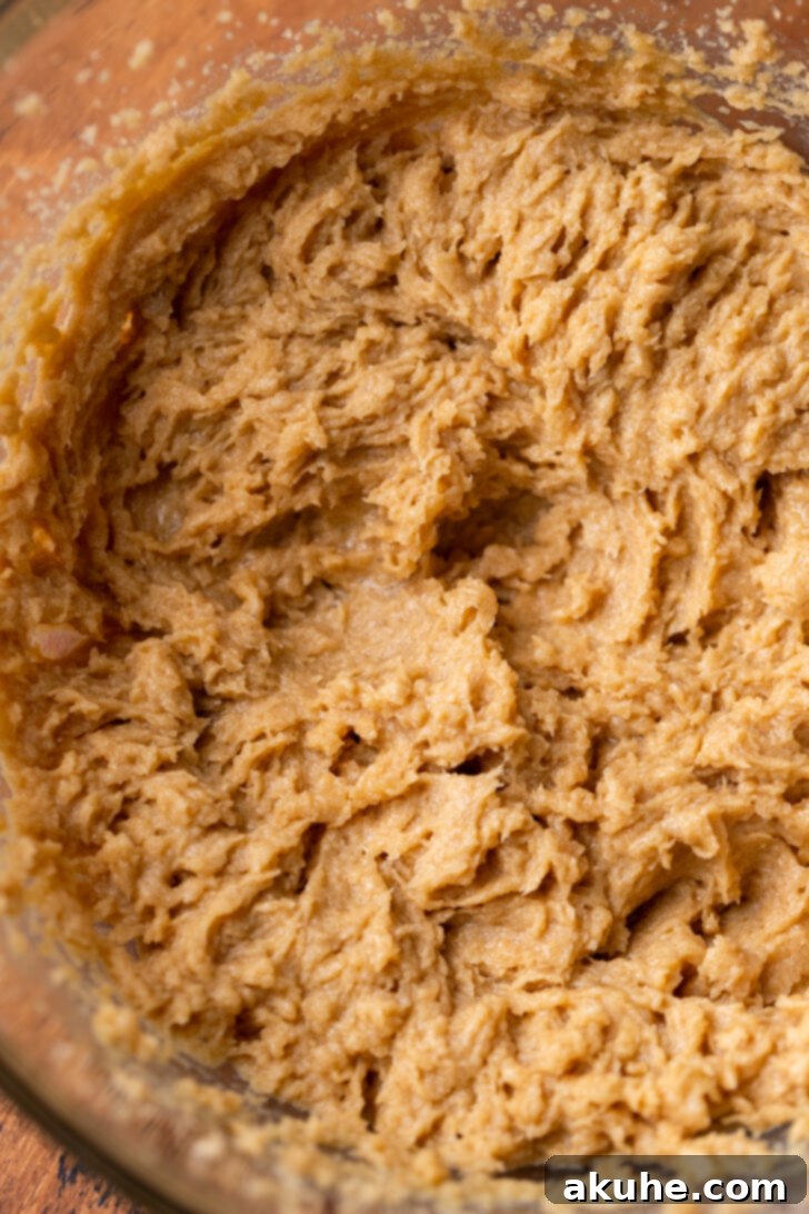 Cookie Dough Stuffed Cookies 4 Wet ingredients (butter, sugars, vanilla, eggs) being beaten together in a large mixing bowl until light and fluffy.