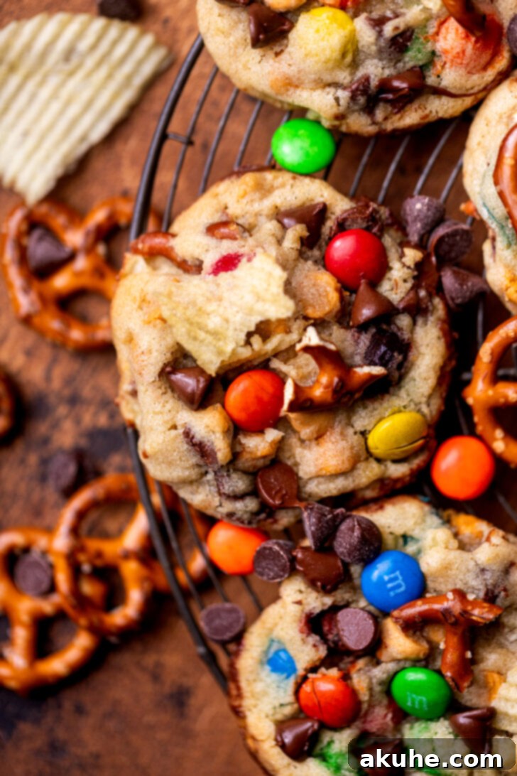 The Everything Cookie 2 A close-up top view of a single, freshly baked Kitchen Sink Cookie, showcasing its diverse mix of potato chips, pretzels, chocolate chips, and M&M's.