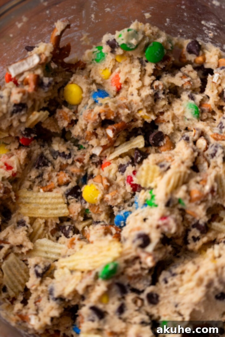 The Everything Cookie 6 Thick, rich cookie dough with various mix-ins visible in a clear glass bowl, showcasing its readiness for baking.