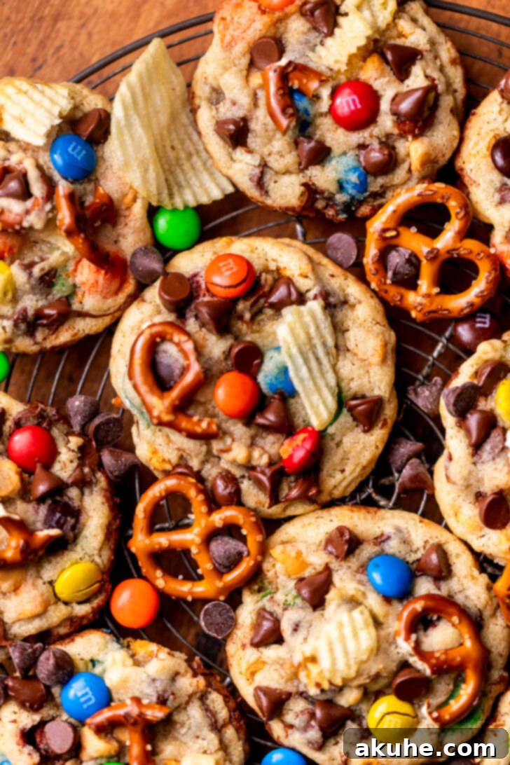 The Everything Cookie 8 A freshly baked batch of Kitchen Sink Cookies cooling on a wire rack, showcasing their golden edges and varied toppings.