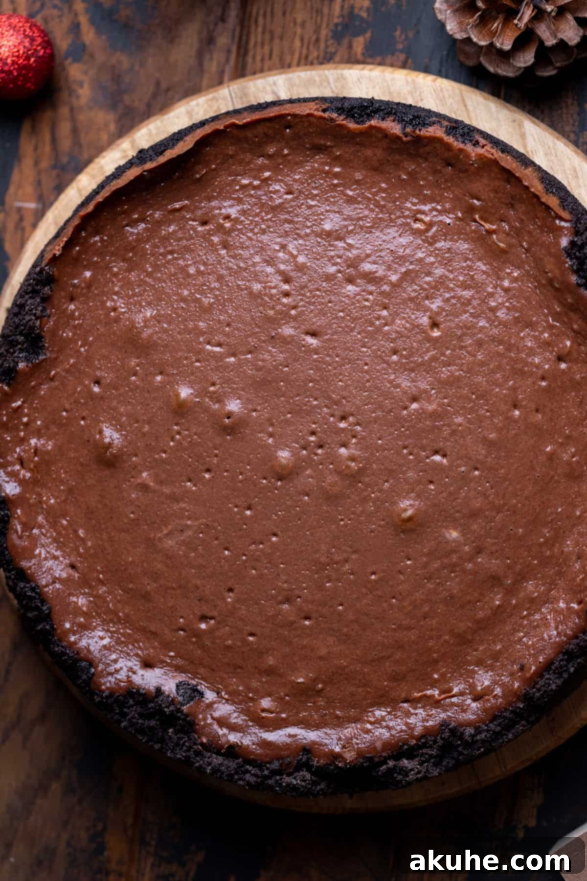Decadent Hot Chocolate Cheesecake 7 A perfectly baked cheesecake, still in its springform pan, resting on a wooden board after baking.