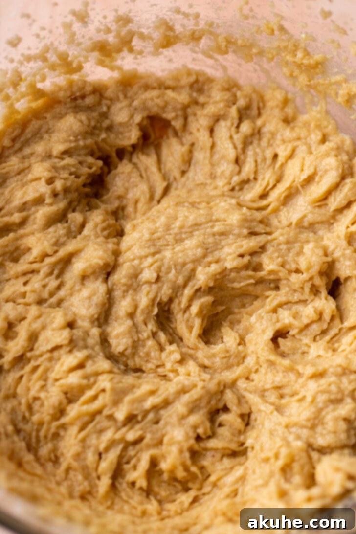 Delectable Peach Cobbler Cookies 4 Wet ingredients (butter, sugar, eggs) being beaten in a large bowl.