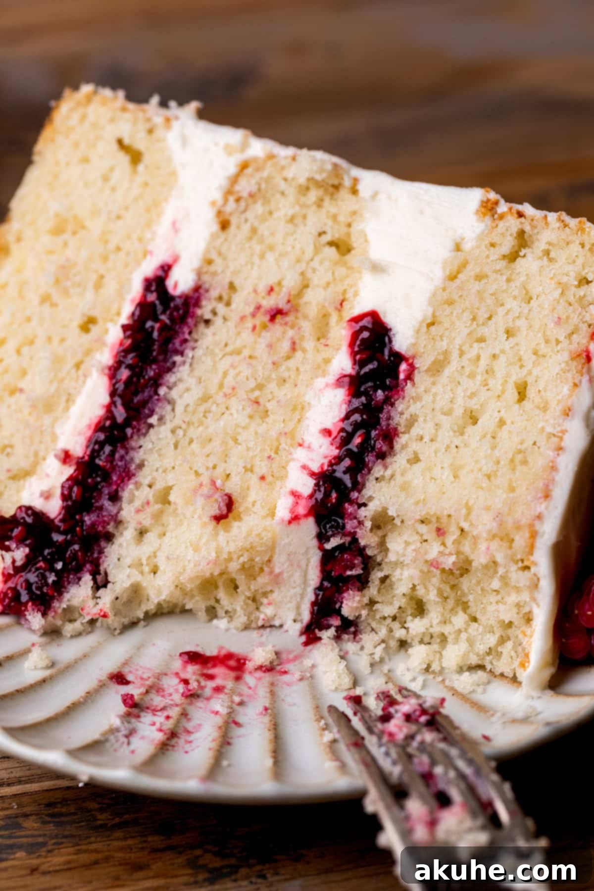 Close up of a delightful slice of white chocolate raspberry cake on a pristine white plate.