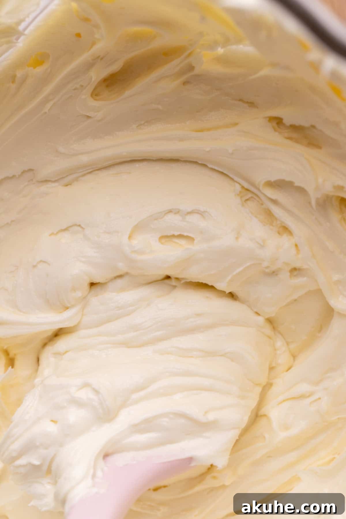 Smooth, creamy white chocolate frosting in a glass bowl, ready for use.