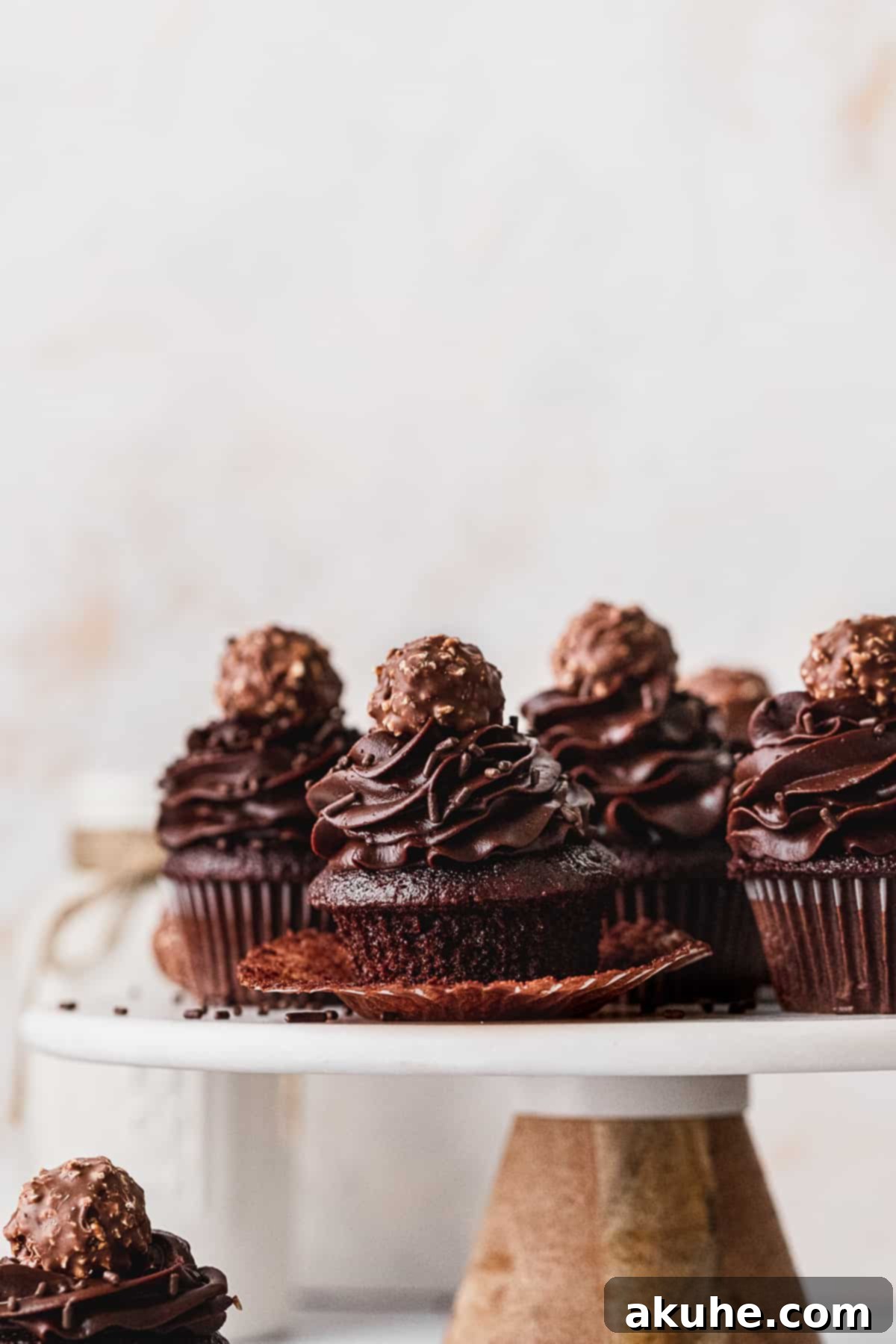 Decadent Chocolate Fudge Cupcakes 4 A perfectly baked chocolate fudge cupcake, unwrapped and displayed on an elegant cake stand, tempting with its rich texture.