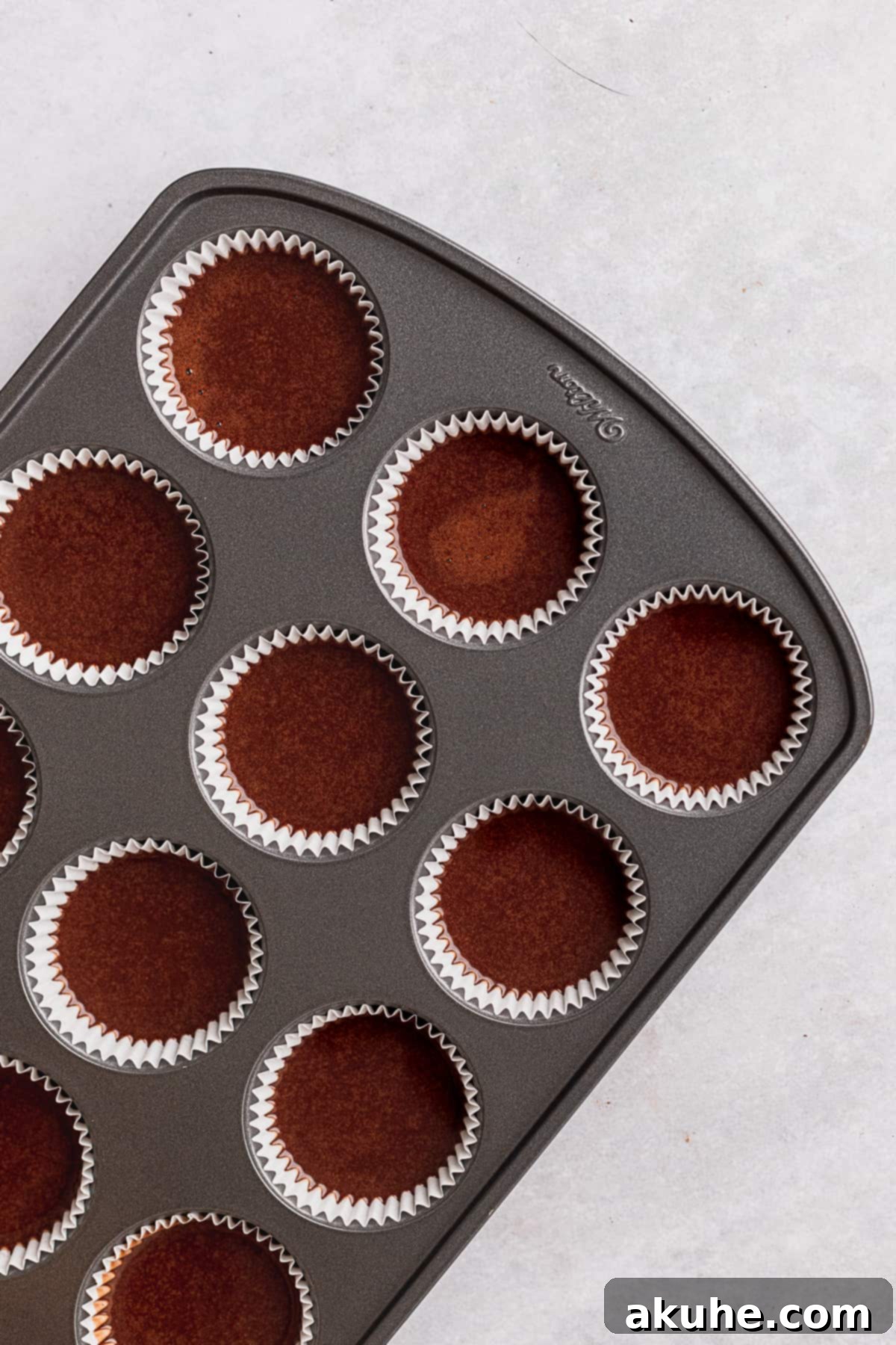 Decadent Chocolate Fudge Cupcakes 6 Prepared chocolate cupcake batter meticulously scooped into muffin liners, ready for baking to become fudgy treats.