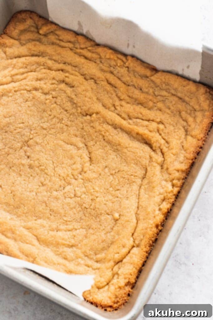 Nostalgic Peanut Butter and Jelly Cheesecake Bars 4 Peanut butter cookie crust pressed into a square baking pan, ready for the next layer